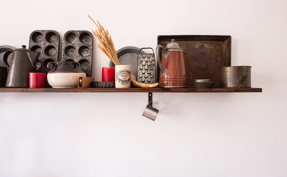 Shelf of Antique Kitchenware Against Whitewash Wall