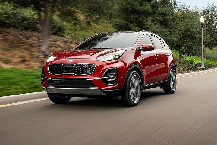 Red 2020 Kia Sportage Driving Down Forest Highway