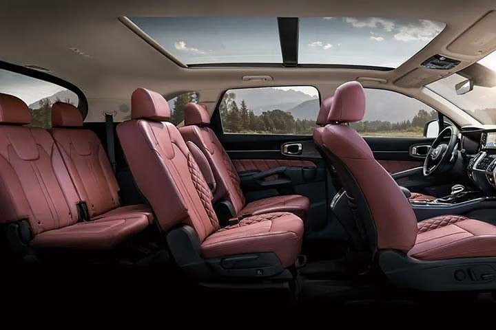 Side view of three rows of seating inside 2021 Kia Sorento in red leather